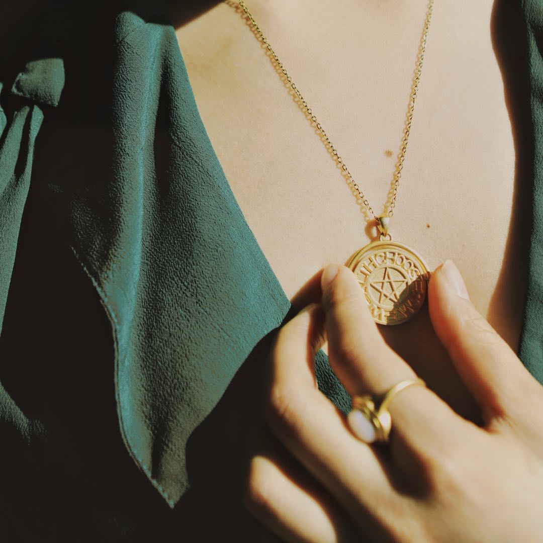 Yiru.jewellery pentacle signet pendant featuring a detailed metal pentacle design on a chain, close-up view.